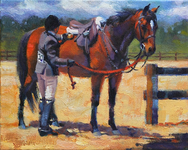 Young woman preparing her horse for a class in a horse show.