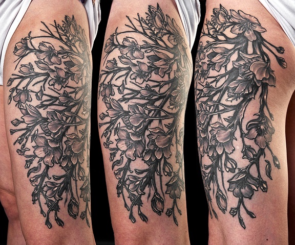 flowers on vines black and grey thigh tattoo