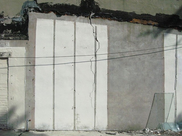 Painted white verticals stripe a shadowed gray wall in Clarksdale, MS, home of the blues, in photograph by Baltimore artist Jo Brown copyright 2012.