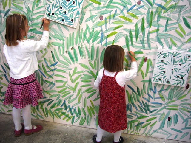 little girls drawing on the wall of an olive grove sanctuary theatrical installation environment by Eugenia Mitsanas for "Olive Grove Project" at Workspace Ltd.