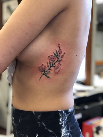 Pink flowers side tattoo by Kc Carew at Gold Standard Tattoo in Bend, Oregon