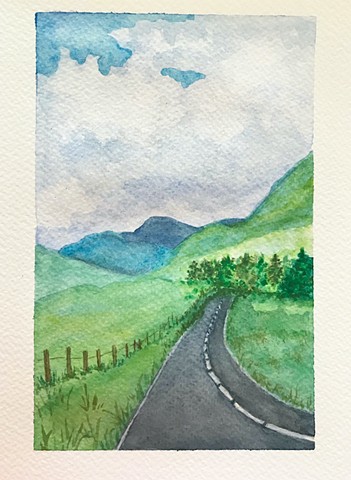 A road winds through Scottish foothills.