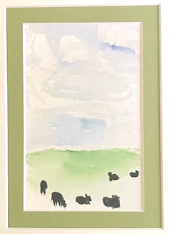 Some black cows relax in a green field under a blue sky.