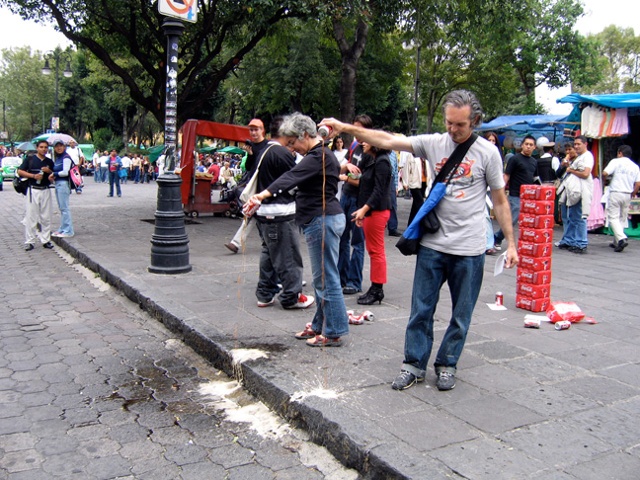 cans of coke are dumped for this art performance with viewer participation in a Mexico City market square