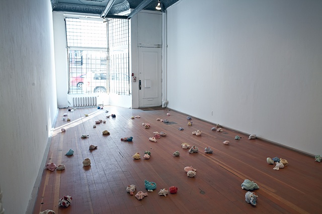 Individually modeled, walnut-sized clay heads, wrapped in baby sleepers and arranged on gallery floor with rain forest photomural 