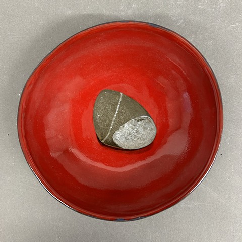 Red ceramic bowl with a painting of a pebble.