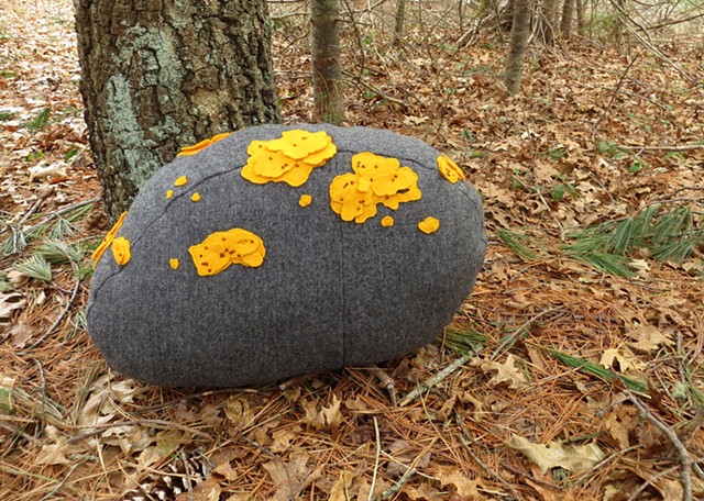 handmade rock shaped wool pillow with yellow applique and embroidered lichen, made by Chelsea Clarke