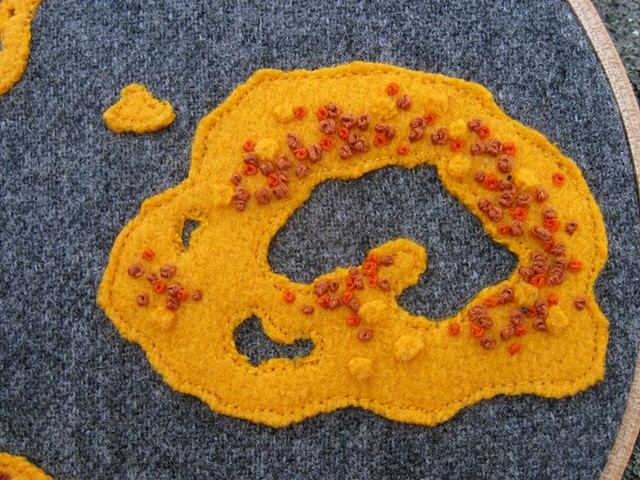 a handmade yellow and orange lichen wall art fiber textile drawing by chelsea clarke with lichen and moss applique and embroidery