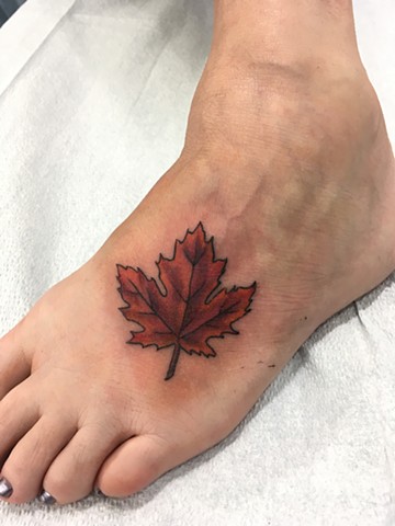 Maple leaf on the top of a foot by Kristin of Strange World Tattoo in Calgary