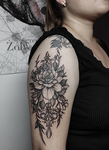 flower tattoo on upper arm in black and grey Strange World Tattoo Calgary Alberta Canada