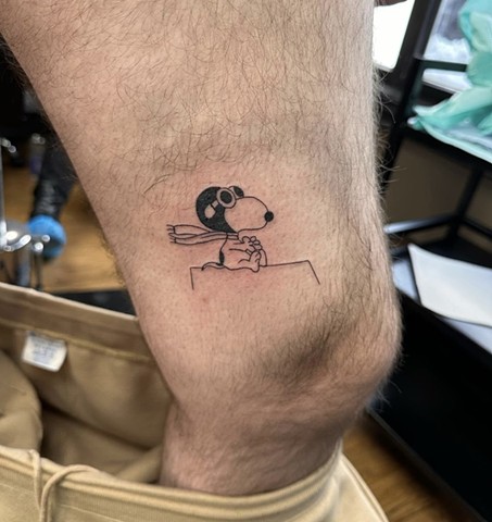 Snoopy flying on thigh cartoon cute peanuts fineline linework black and grey feminine tattoo shop artist strange world tattoo Calgary alberta Canada 