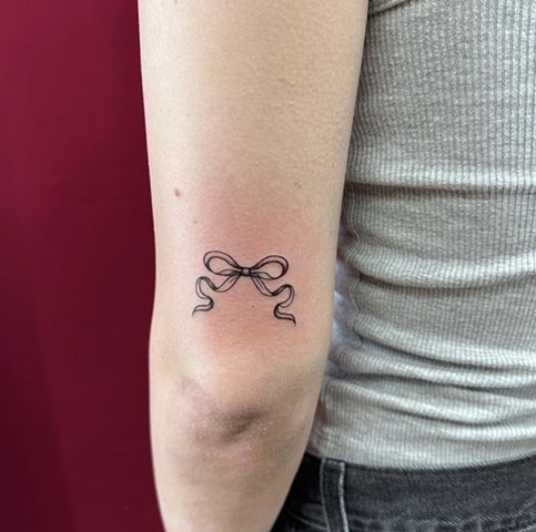 Dainty bow on back of forearm strange world tattoo fineline Calgary tattoo artist