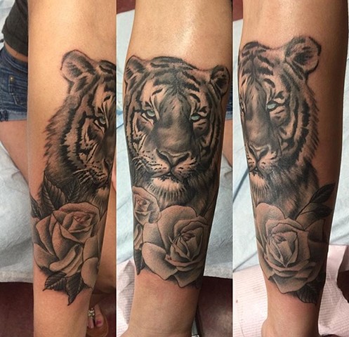 Tiger tattoo with roses in black and grey on forearm Strange World Tattoo Calgary, Alberta Canada