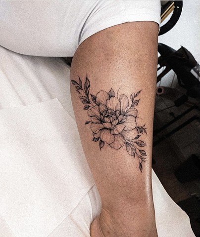 flower tattoo on calf in black and grey Strange World Tattoo Calgary Alberta Canada