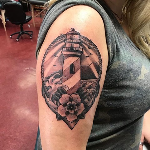 Traditional tattoo style of lighthouse in black and grey on upper arm Calgary Alberta Canada Strange World Tattoo 