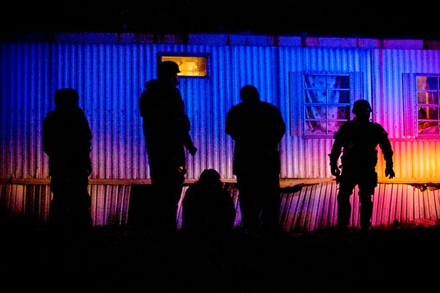 Officers stand watch over a pair of detained men after a police raid on a home suspected of drug trafficking on Jan. 6, 2010 in Wade, North Carolina.