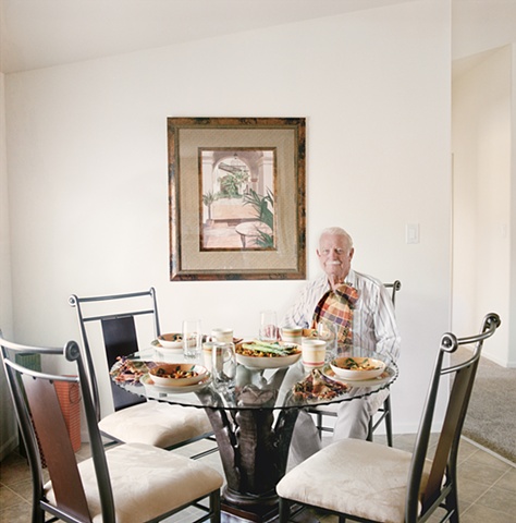 Man seated at table with fake food, manufactured display home, © Amy Eckert www.amyeckertphoto.com