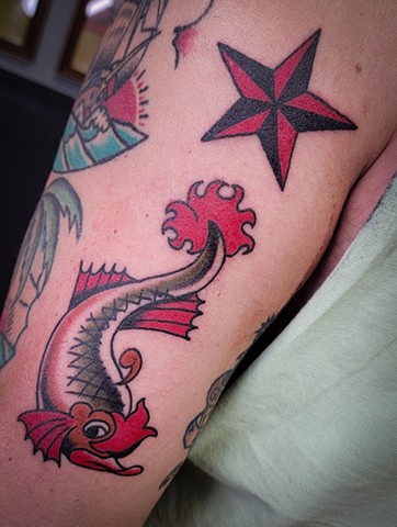 sailor jerry traditional tattoo of dolphin fish with nautical star on upper arm by Gina Matuo of Copper Fox Tattoo in Kissimmee Florida best tattoos near me