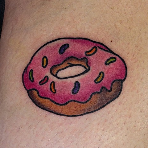 traditional tattoo in full color of a Pink donut seen on The Simpsons by Gina Matuo of Copper Fox Tattoo in Kissimmee Florida best tattoo shop near me