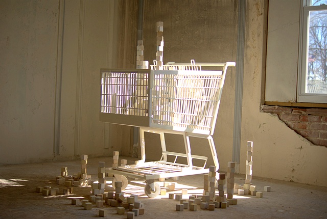 Sculpture of shopping cart and blocks made from reclaimed lumber.