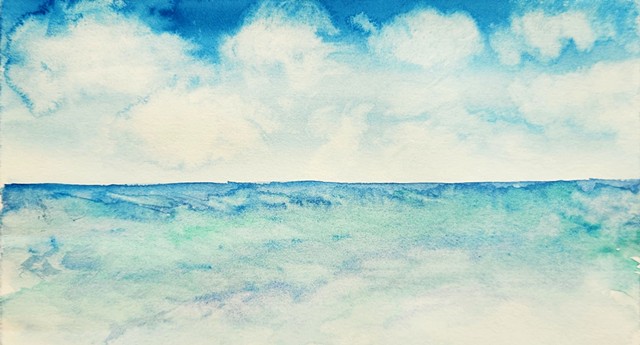 fluffy white clouds in a blue sky above a beautiful blue and green ocean