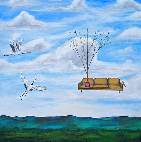 two crains flying in blue sky.  yellow midcentury modern couch in the air with hawk on it.  potted tree on cocuch.  cows eating in green field.  big horn mountains painting