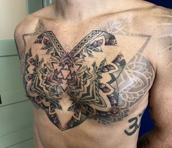This is a geometric chest piece tattoo done by Amanda Marie tattooer in Los Angeles California at her private studio in San Pedro ace of wands tattoo it is a sacred spiritual piece that has intention and meaning expressed through a mandala geometry