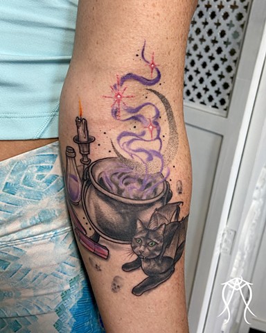She sits guarding her witch’s brewing herbal potion under the waxing moon a tattoo of a cat kitty familiar done in color by female tattoo artist Amanda Marie in her private tattoo and tarot studio in east coast Ithaca Scipio center New York 