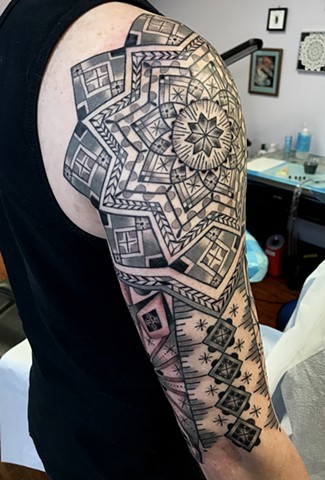 this is a tattoo of  a Ukrainian Easter Egg Inspired Half Sleeve done in a geometric ornamental style by Amanda Marie female tattoo artist and tarot reader in Los Angeles California 
