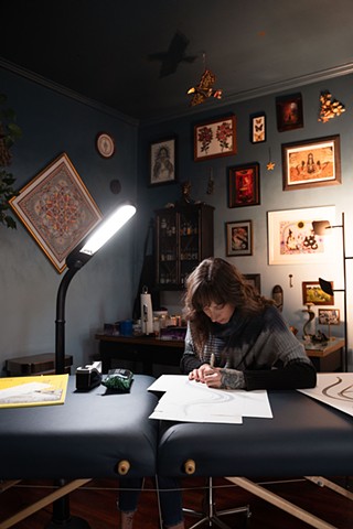 Amanda Marie female tattoo artist and tarot reader drawing in her private tattoo studio in Scipio center Cayuga county New York 