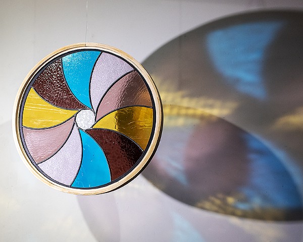 Natalie Hunter %Aperture 03, Light Unfolding (Shades of Dawn)% 2026 Glass, lead, zinc, hand shaped and curved oak, light. 20" round.  Produced with the generous support of the Canada Council for the Arts.