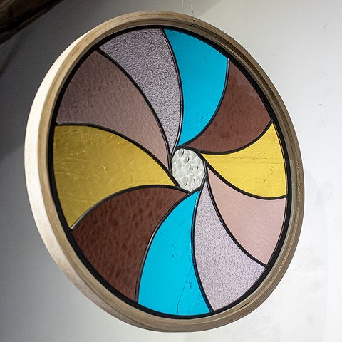 Natalie Hunter %Aperture 03, Light Unfolding (Shades of Dawn)% 2026 Glass, lead, zinc, hand shaped and curved oak, light. 20" round.  Produced with the generous support of the Canada Council for the Arts.