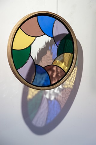 Natalie Hunter Aperture 02, Light Unfolding (Shades of Dusk) 2026 Glass, lead, zinc, hand shaped and curved oak, light. 20" round.  Produced with the generous support of the Canada Council for the Arts.