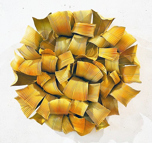Circular modern wall sculpture accentuated by gold, yellow and ochre enamel paint on aluminum pleated metal.