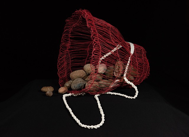 A red burden basket carrying rocks covered in panthyhose