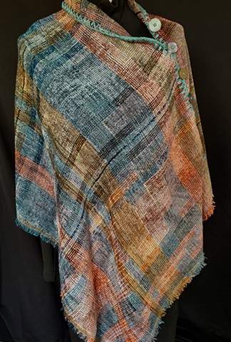 Handwoven poncho of rayon chenille, cotton and bamboo yarns.  Hand-embellished with crochet and buttons.