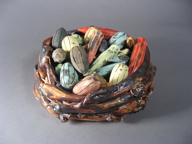Pods are slipcast and twigs basket it porcelain. Underglazes and oxides are used for color.
