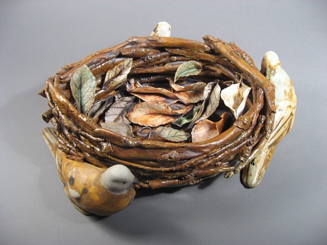 Slip cast birds surrounds twig basket. Leaves are loose in the basket. Judith Rosenthal