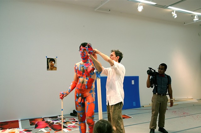 A male participant’s body is photographed in a pose of his choosing in advance of the performance. During the performance the printed images are applied directly onto the corresponding parts of the performers body.