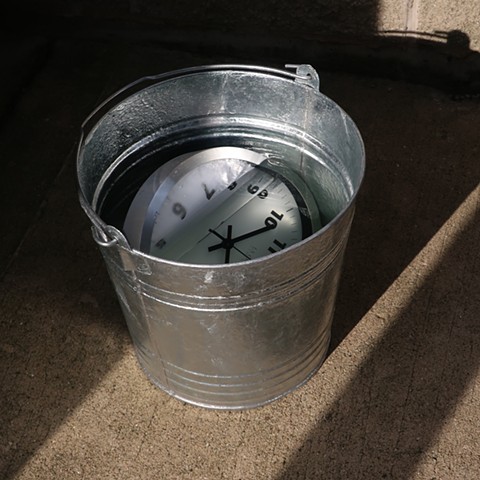Robert Fields, “…and so, how’s it with you?” 2020. 12" H x 13" W, 14 QT Galvanized pail, water, wall clock (metal, plastic & glass), battery not included, and piss. Art. Conceptual Art. Art in time of isolation. 