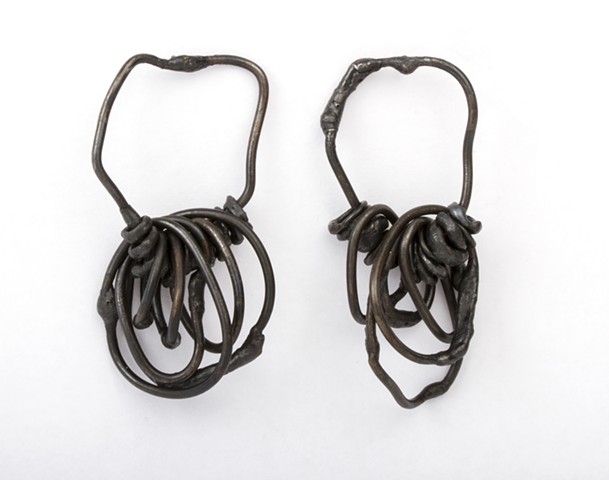 an asymmetrical pair or earrings composed of welded steel wire chain links and sterling silver.