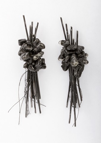 a one-of-a-kind pair of asymmetrical earrings composed of welded steel clusters of wire, sterling silver and handmade crushed graphite beads covered in resin and attached with black thread