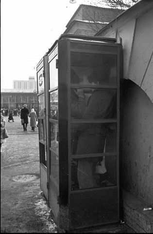 Two men in fur hats in a telephone booth, Moscow
