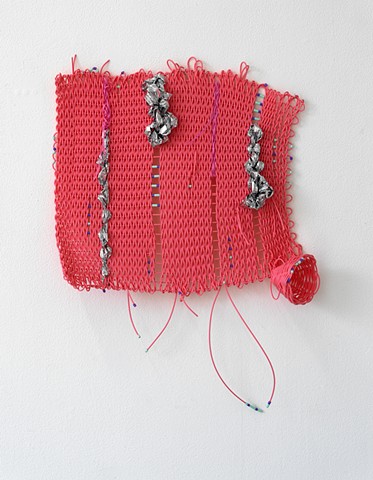 wall-based twined work by José Santiago Pérez made with plastic reed, perler beads, and mylar emergency blankets