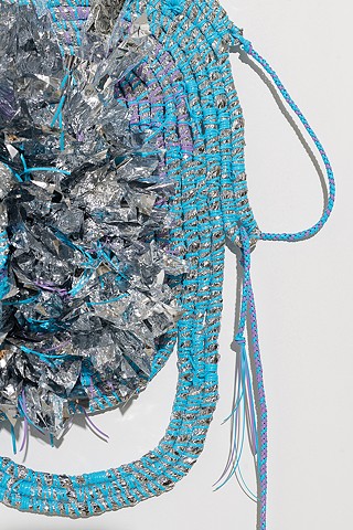 detail of wall based abstract coiled basket made with emergency blankets and baby blue and lavender plastic lacing by José Santiago Pérez