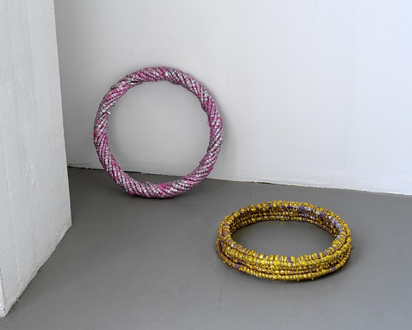coiled mylar rings; one leans on the wall and one is placed on the gallery floor