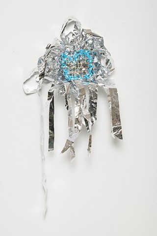 sculpture made with knotted silver mylar emergency blankets, silver and gold leaf, plastic mesh, and netted baby blue plastic lacing with baby blue plastic beads by José Santiago Pérez