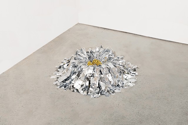 round floor sculpture made from hand netted nylon and knotted silver and gold mylar emergency blankets around a clear silicone ring by José Santiago Pérez