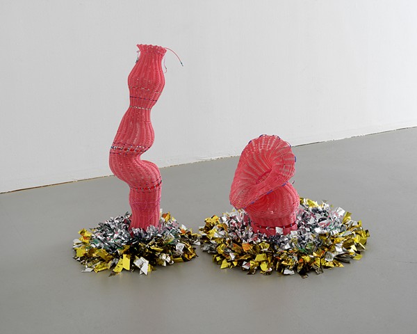 two twined sculptures made of plastic reed by José Santiago Pérez are set in close proximity to one another on beds of knotted mylar emergency blankets