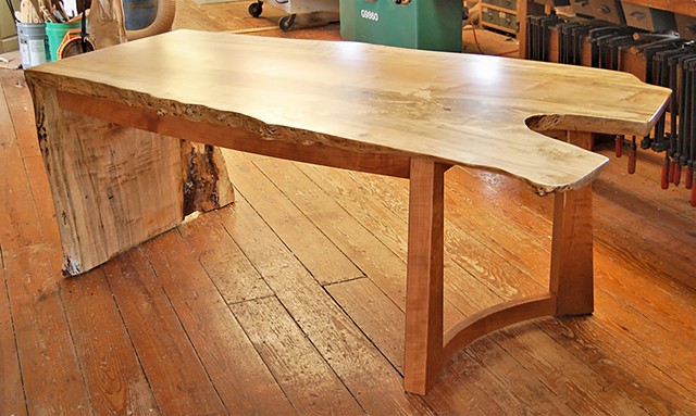 Arnold desk, featuring a one-piece waterfall top made from highly figured maple, locally sourced.  It sits on a cherry base with a single row of drawers.  Approx. 38 x 84 x 30 high.